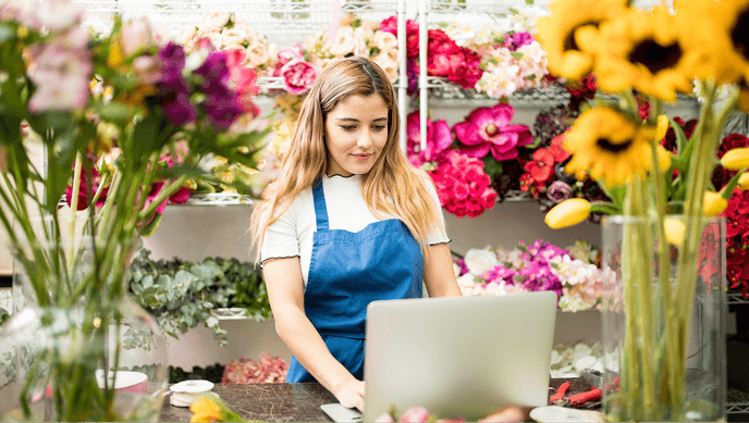 A woman working on a laptop in a flower shop
